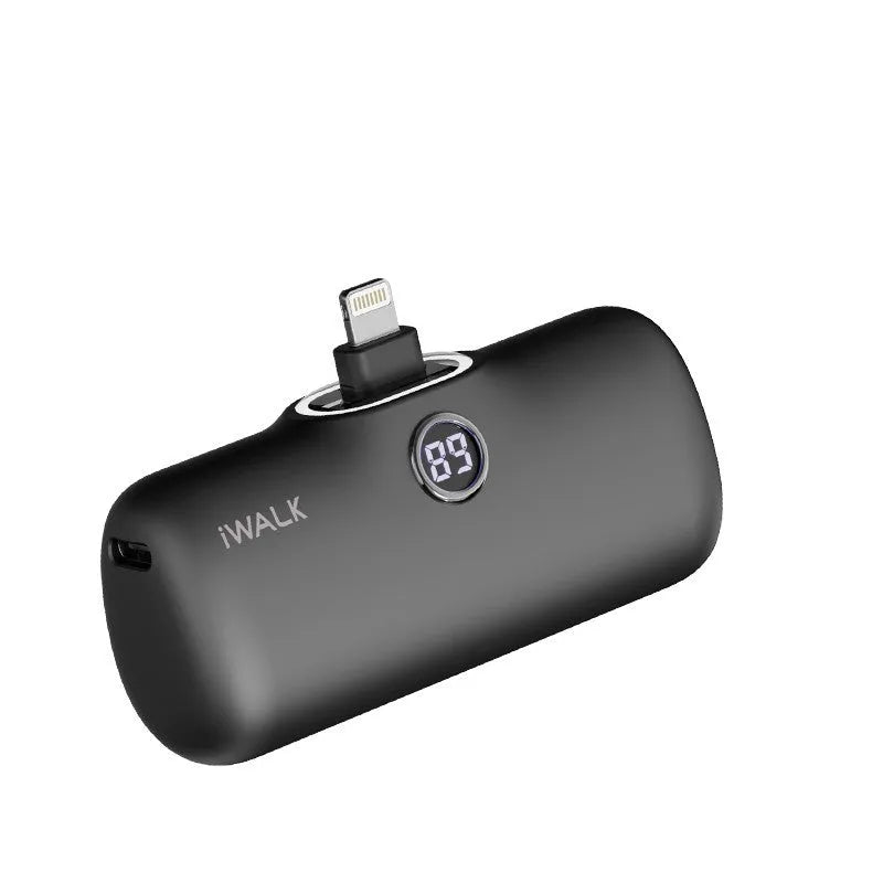 Compact white lipstick-shaped power bank with a digital screen, shown next to a smartphone on its wireless charging pad.