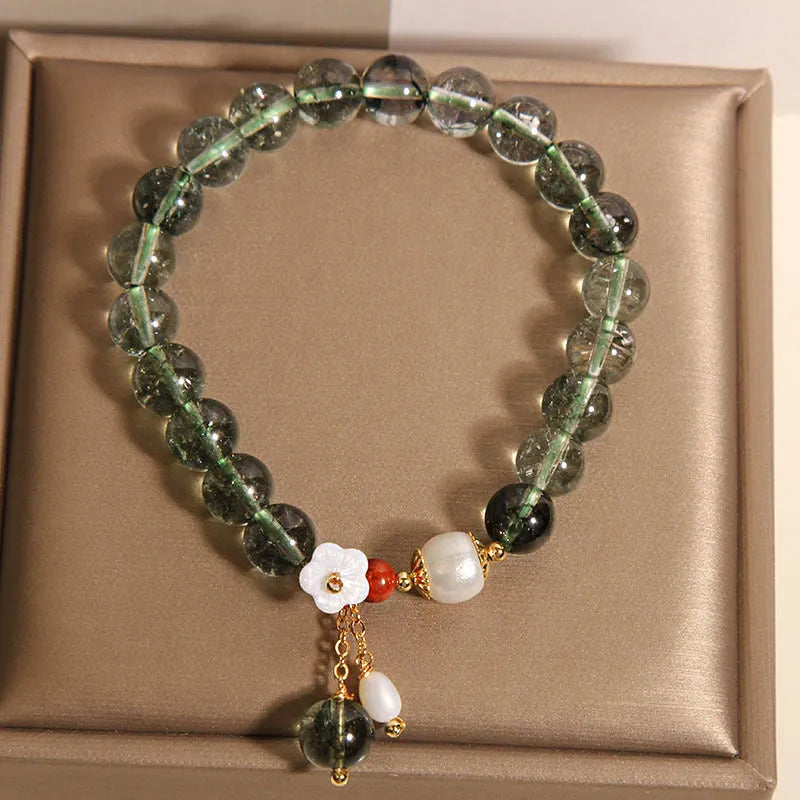 Green phantom quartz crystal bracelet with shell flower charm on a woman's wrist