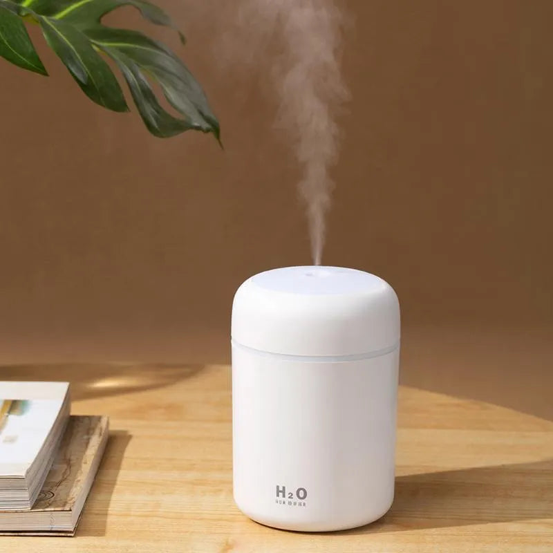 Pink, white, or navy blue USB mini humidifier with colourful lights on a desk