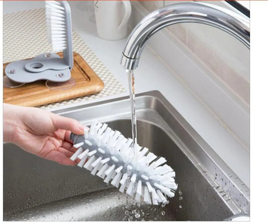 Grey kitchen cleaning brush with two brush heads and suction cups for wall mounting