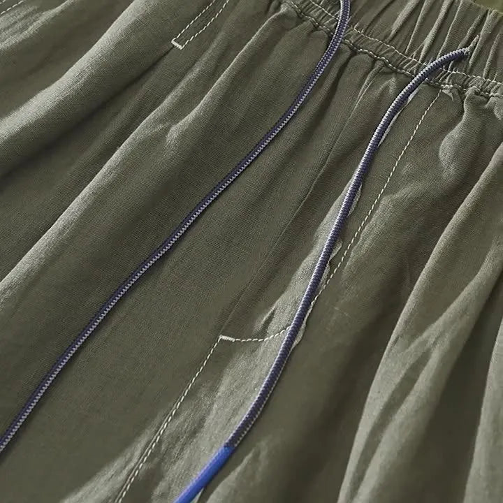 Men's loose fit linen shorts in green on a neutral background