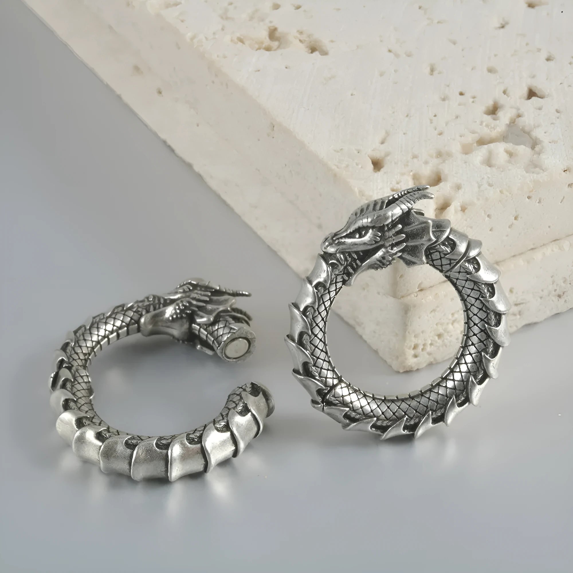 Large antique silver dragon-shaped hollow out copper auricle earrings on a white background.