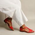 Red women's sandals with a square buckle and herringbone toe holder on a casual low-top.