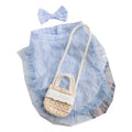 Small dog wearing blue country outfit with matching bow and small woven crossbody bag