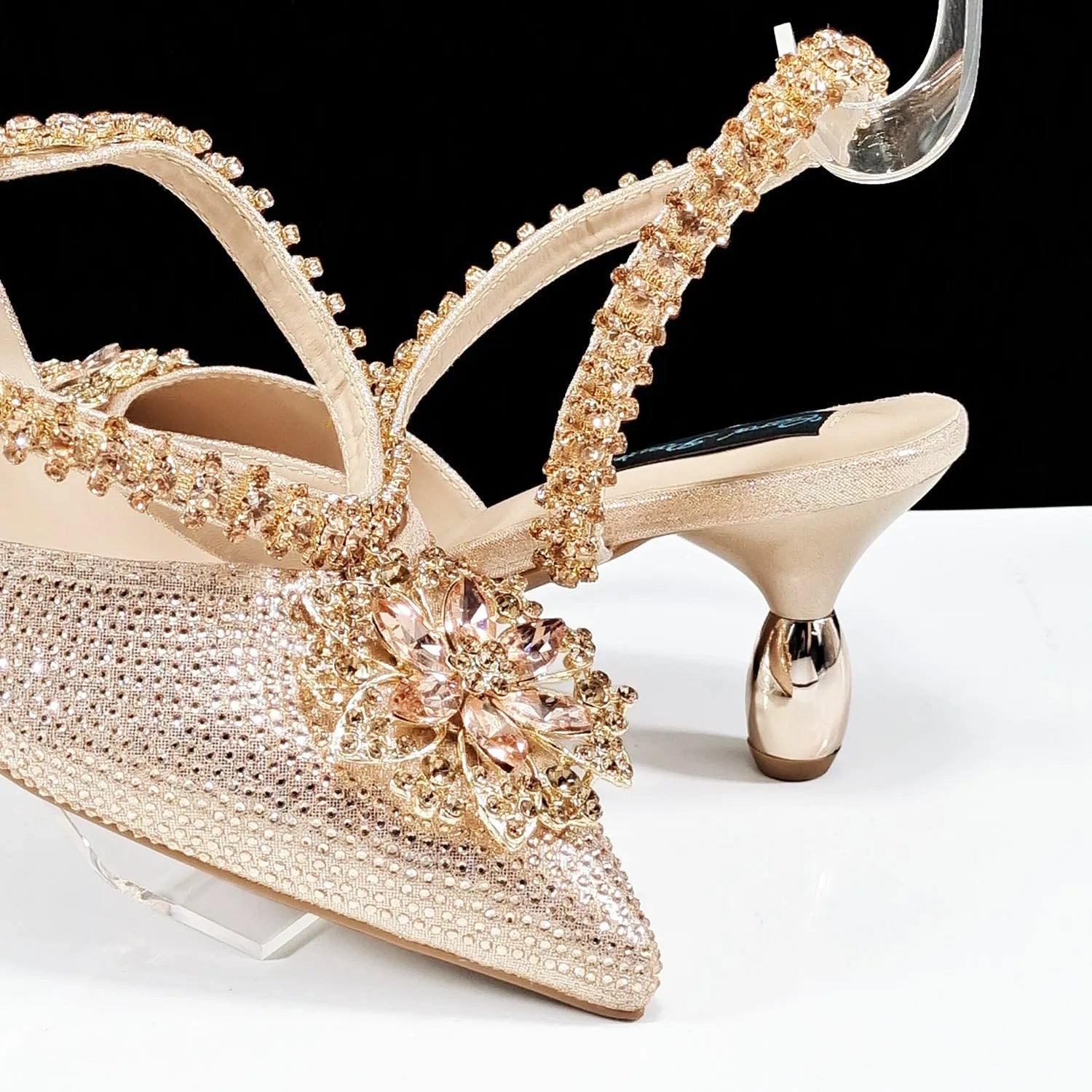 Women's black high-heel ankle strap sandal with rhinestone flower buckle and matching hard clutch bag.