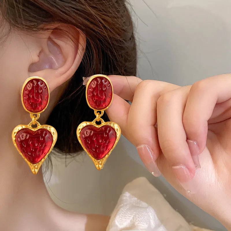 A pair of purple heart-shaped alloy stud earrings with a pleated oval texture and silver post.