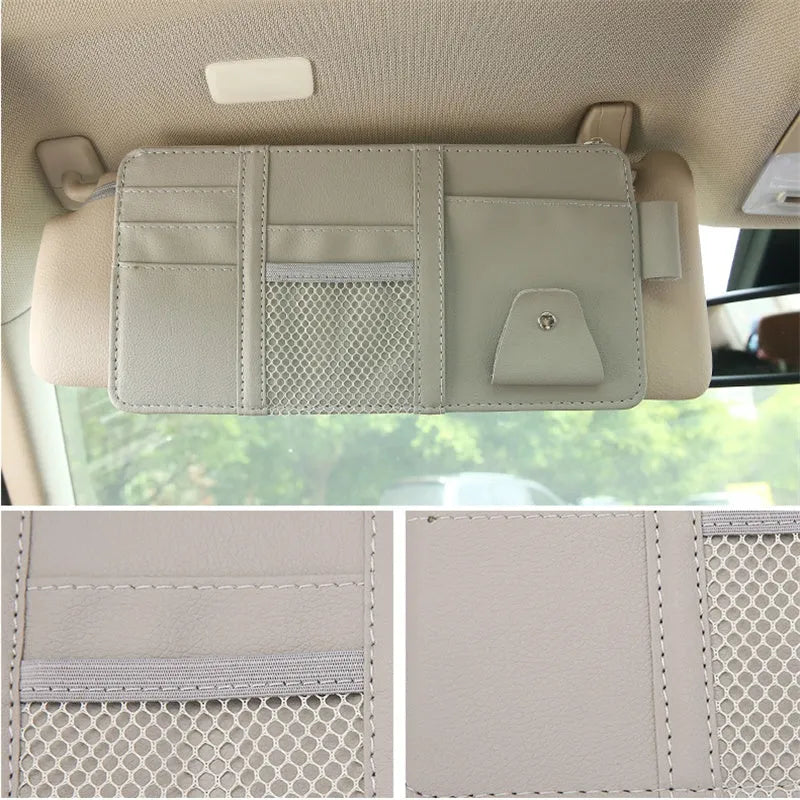 Beige car sun visor storage bag with seven open pockets, zip pocket, sunglasses clip, and pen holder on vehicle visor