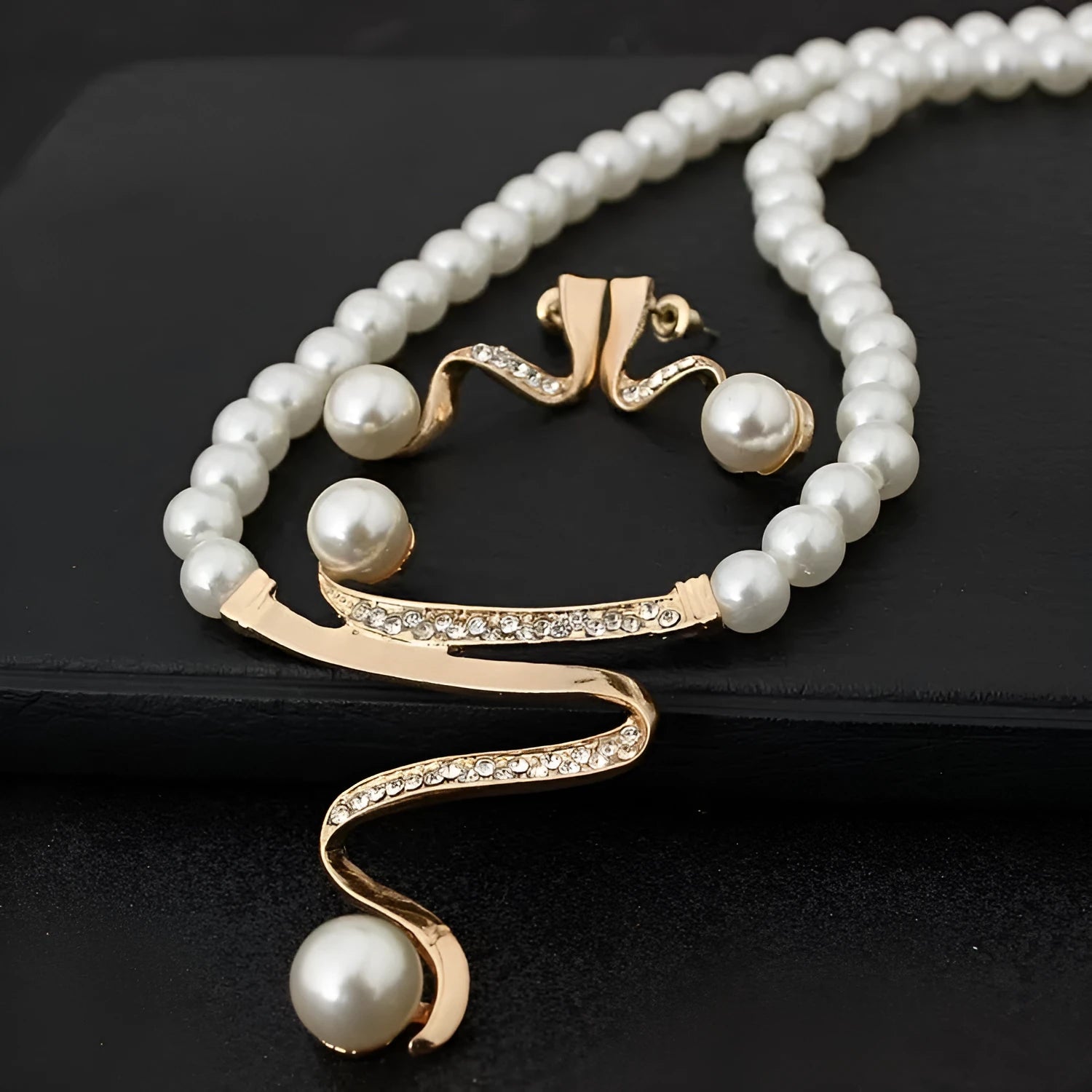 Gold electroplated pearl necklace and drop-shape earrings set on a jewellery display.