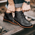Men's black military Martin boots with rubber sole and lace-up closure on a work site