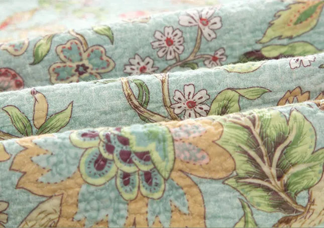 Blue American floral pattern cotton quilted bedspread set of three pieces laid on a bed.