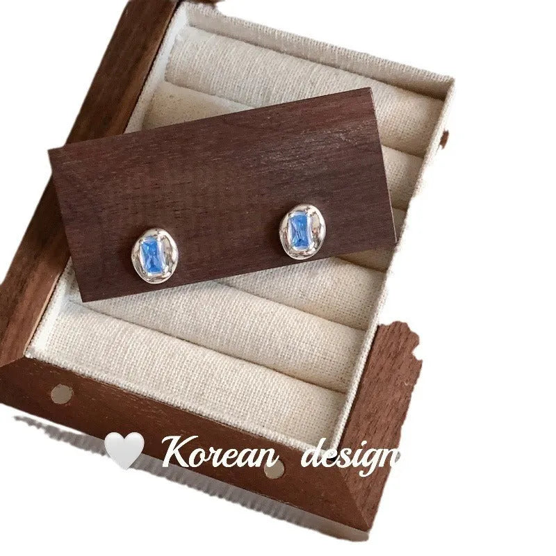 Sterling silver earrings with heart-wrapped oval blue diamond design and electroplated finish