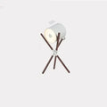 Modern three fork wooden floor lamp with an acrylic shade in a living room setting.