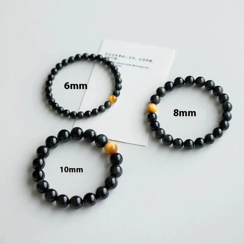 Black obsidian geometric bracelet with spherical beads on a wrist, showing unisex Korean style.