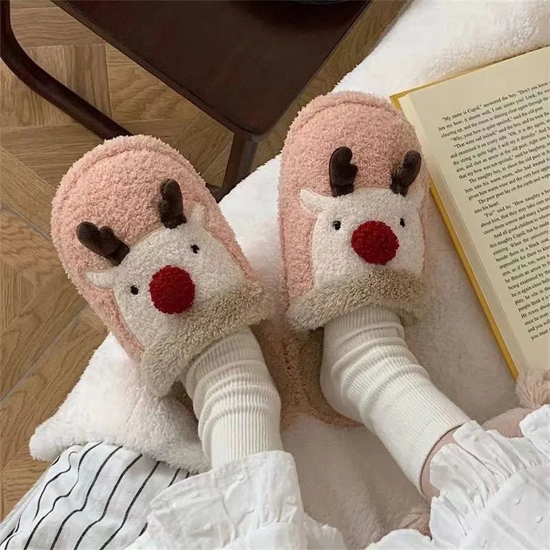 Women's brown Christmas elk plush slippers with non-slip PVC sole on a wooden floor.