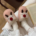 Women's brown Christmas elk plush slippers with non-slip PVC sole on a wooden floor.