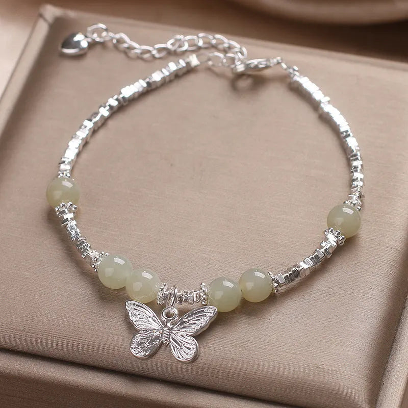 Hetian jade beads bracelet with silver butterfly pendant on a white background