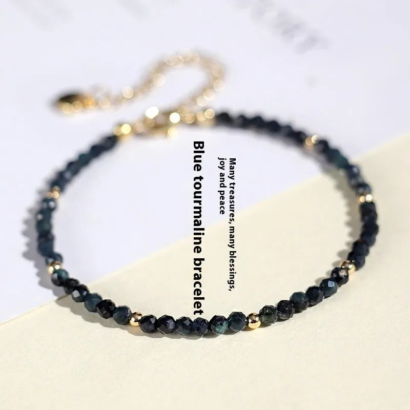Close-up of a women's bracelet with 3mm blue tourmaline cut beads and silver-toned spacer beads on a wrist.