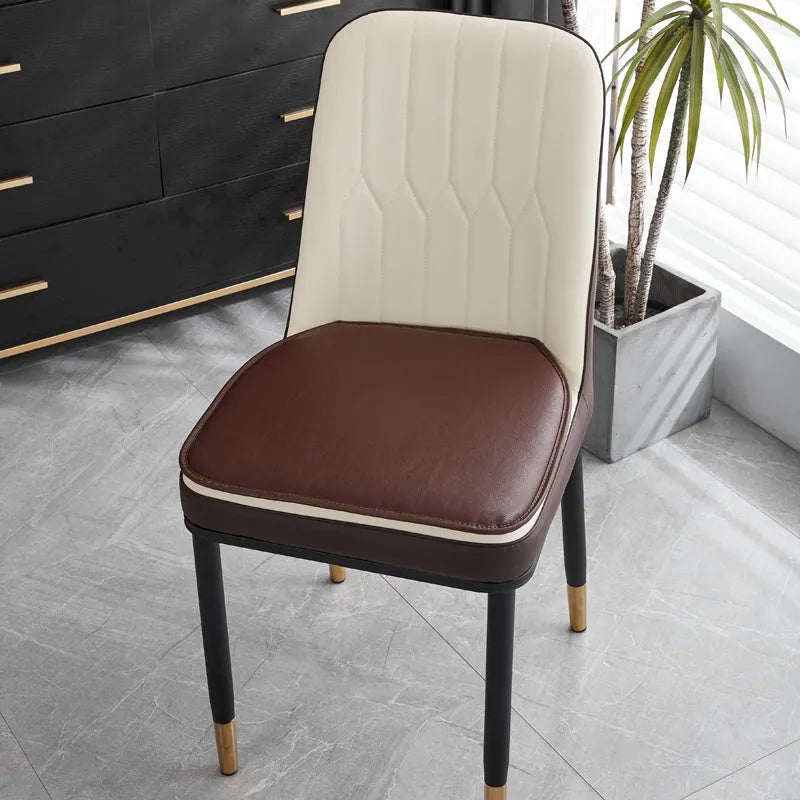 Orange leather horseshoe-shaped seat cushion on a wooden dining chair.