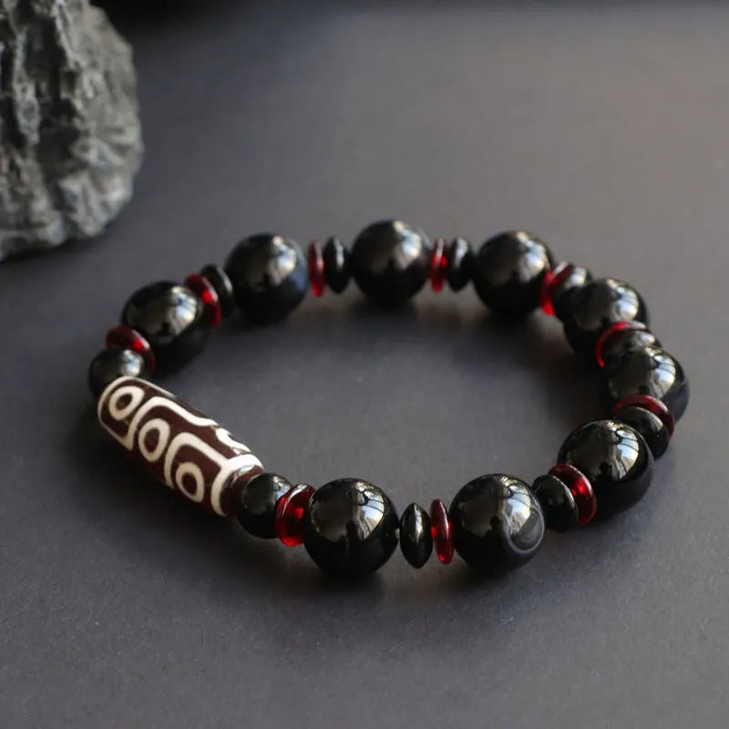 Hand-woven black agate Dzi bead bracelet with chalcedony detail on a wrist.