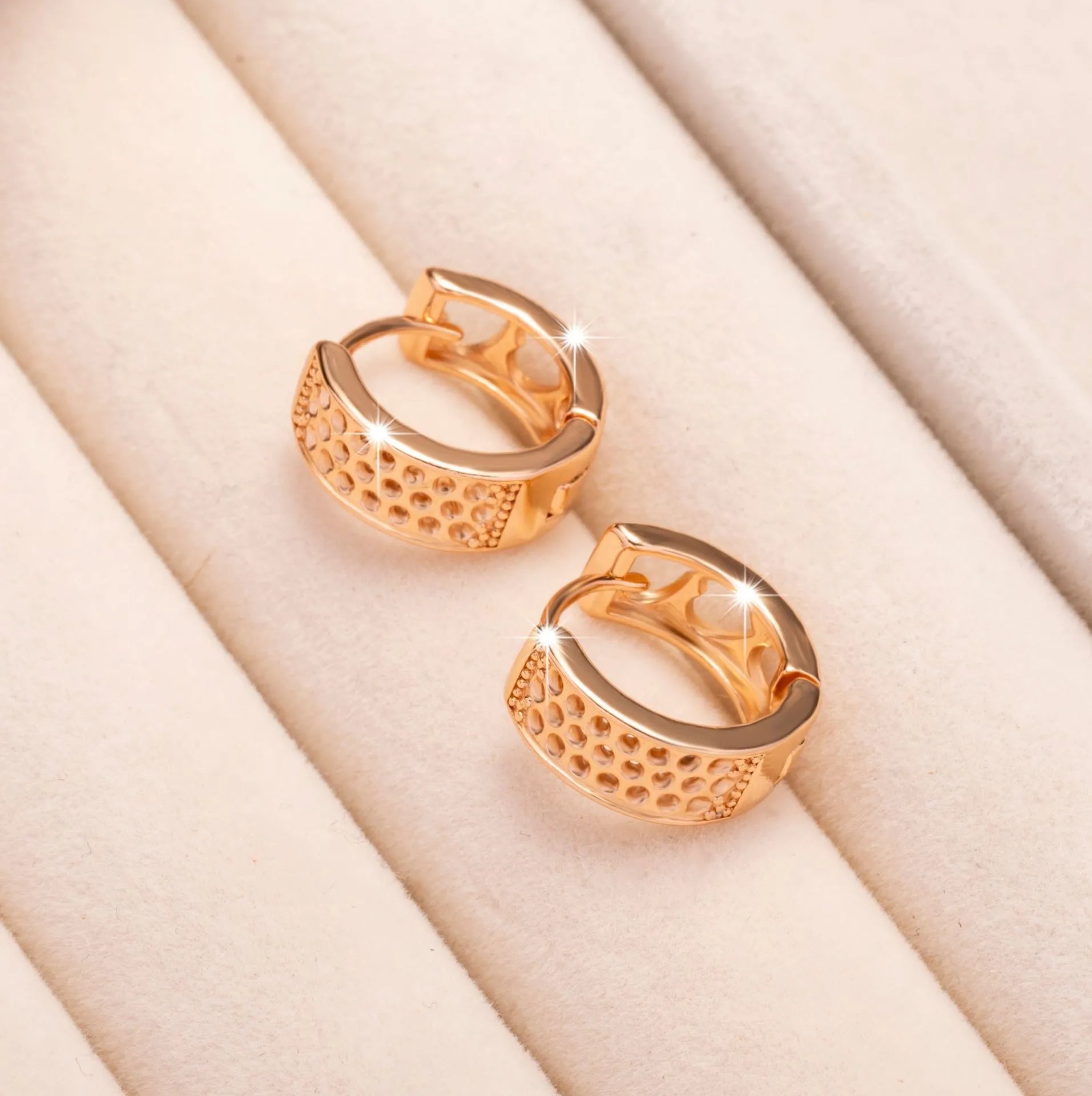 Rose gold circular earrings with three hollowed-out heart shapes.