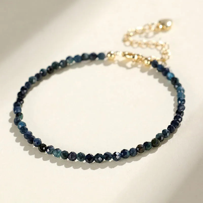 Close-up of a women's bracelet with 3mm blue tourmaline cut beads and silver-toned spacer beads on a wrist.