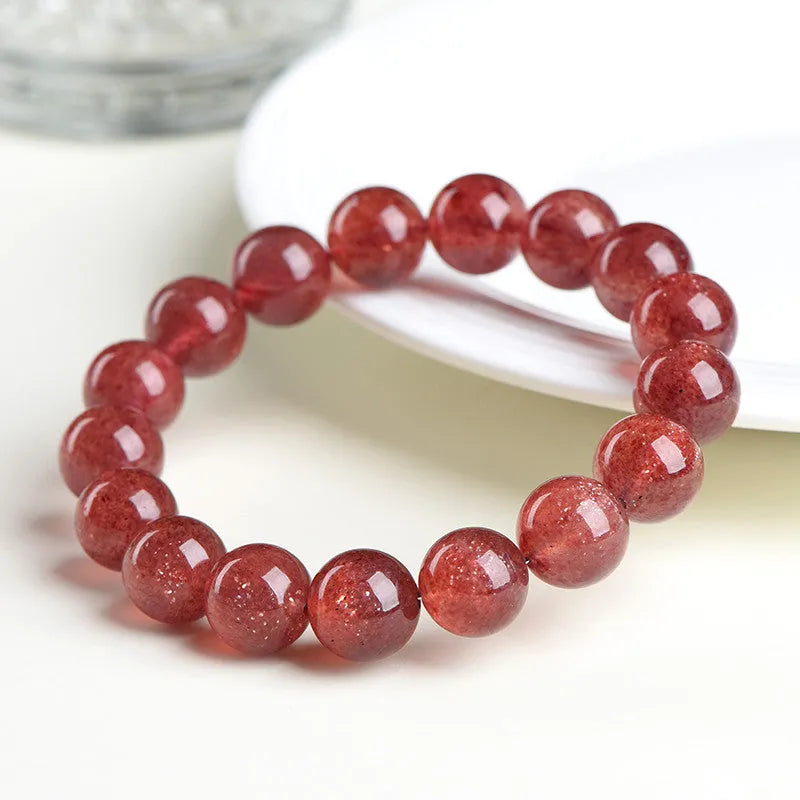 A stretch bracelet with round, pink strawberry quartz beads on an elasticated cord, shown in different size options.