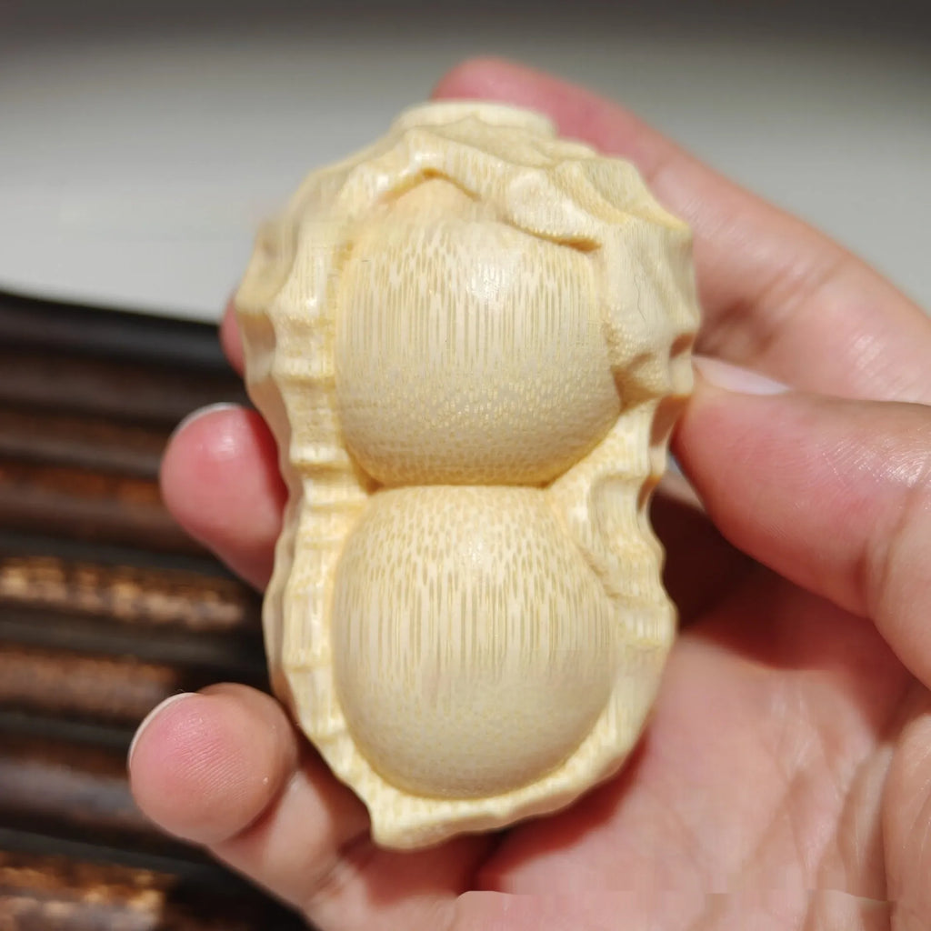 Solid natural bamboo carving of a peanut ornament on a wooden surface