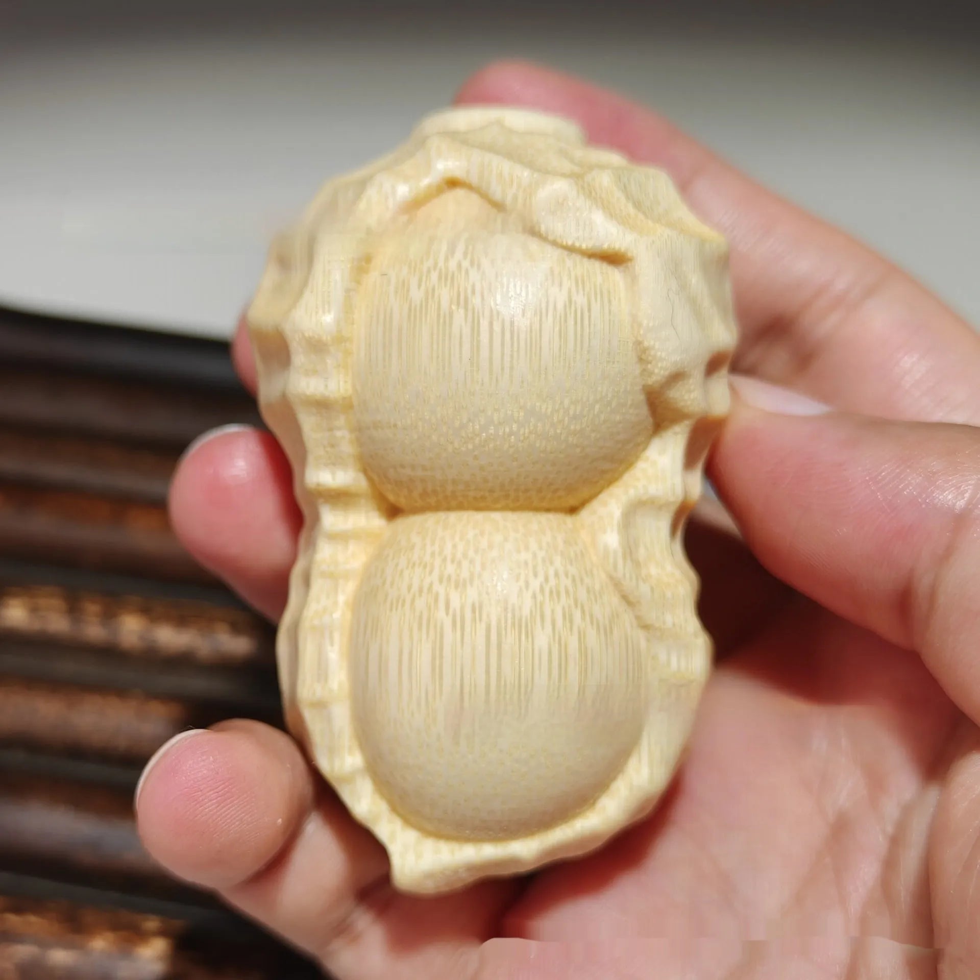 Solid natural bamboo carving of a peanut ornament on a wooden surface