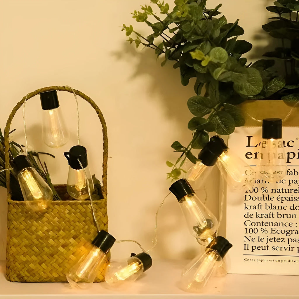 Retro infusion bottle shaped solar outdoor string lights draped in a garden setting.