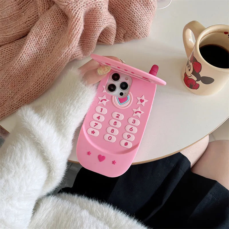 A light pink silicone iPhone case shaped like a flip phone with a built-in mirror on the front.