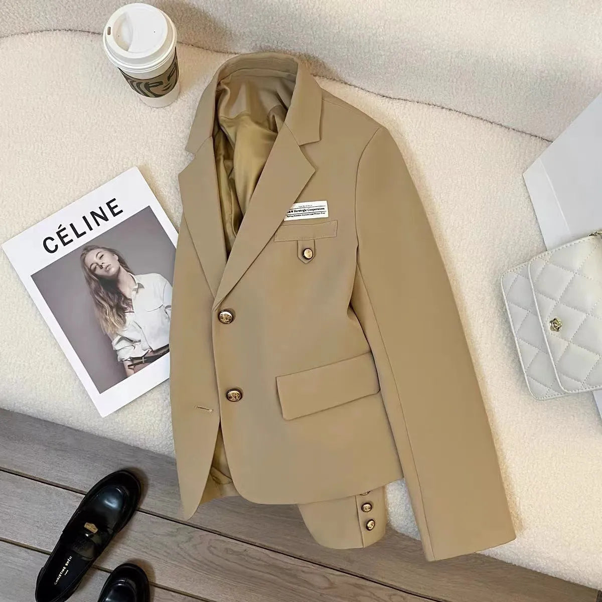 Black loose-fit women's short suit coat with long sleeves and pockets on a hanger.