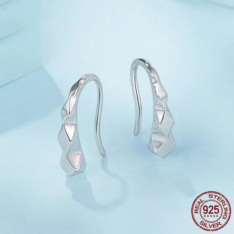 Close-up of S925 sterling silver rhombus earrings with diamond plaid pattern on a neutral background