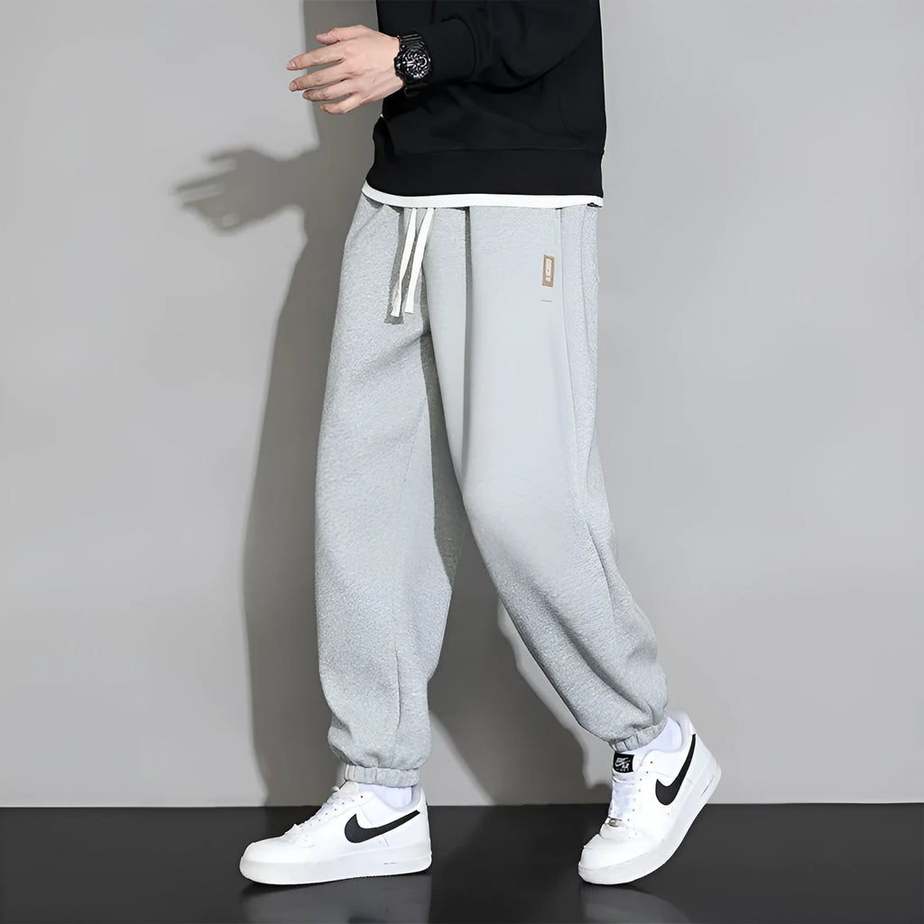 Men's loose grey cotton polyester sports trousers with elastic drawstring waist, laid flat.