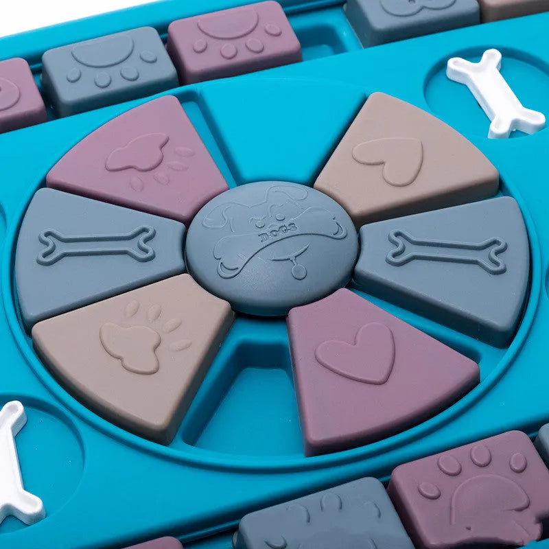 Blue plastic interactive dog puzzle feeder with sliding panel and four corner handles on a non-slip base