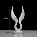 Mini synthetic resin decoration in silver and gold angel wing style on a shelf