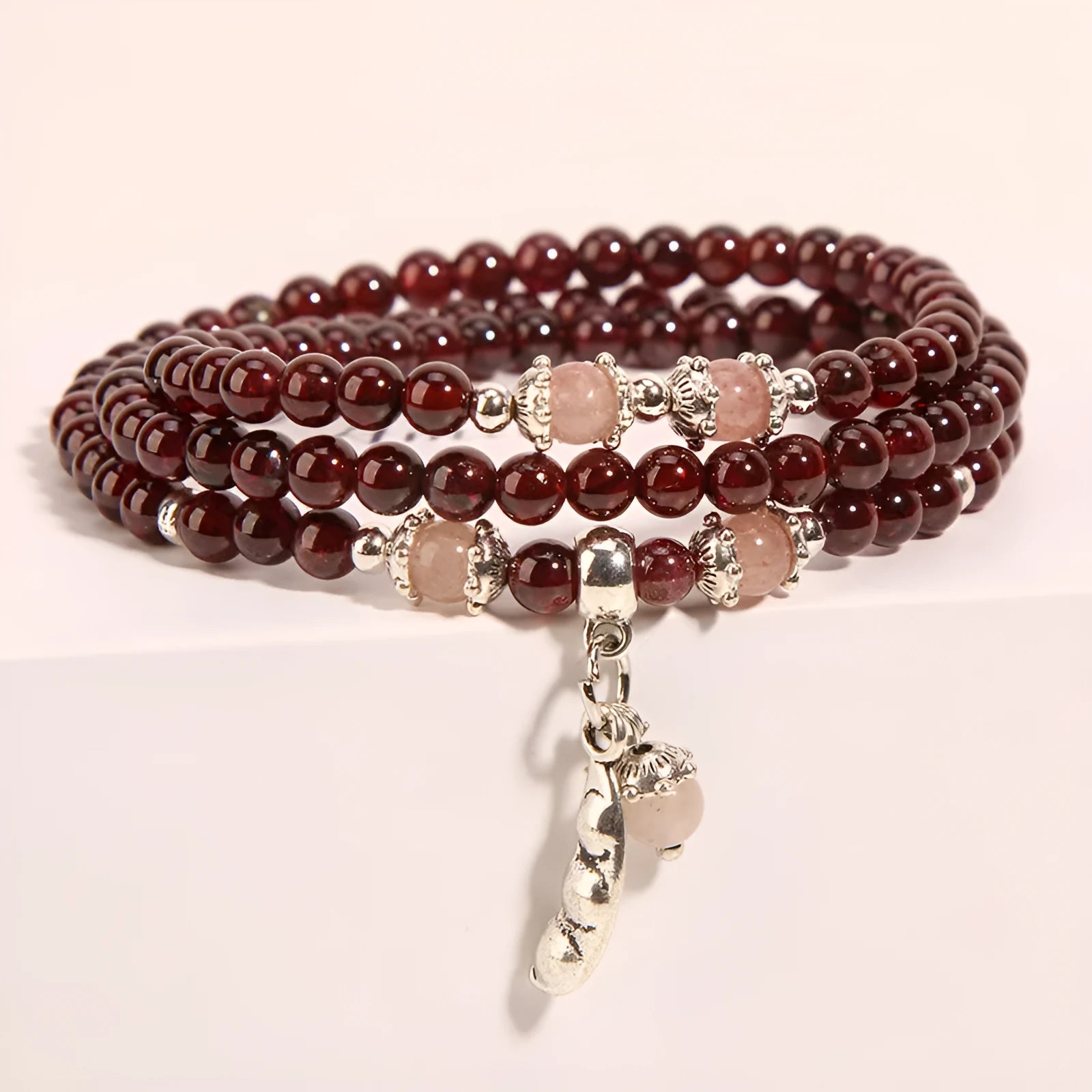 Wine red garnet crystal bracelet with flower-shaped charm on a model's wrist.