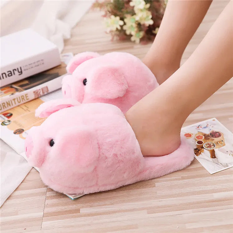 Pink pig-shaped plush indoor slippers with a cute animal face design, shown on a plain background.