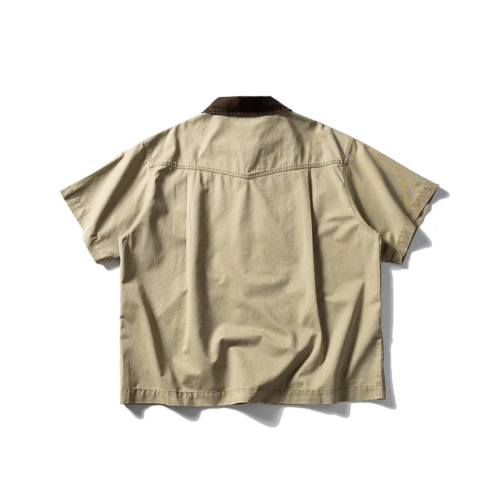 A khaki-coloured, short-sleeved overalls shirt with a loose cardigan style on a hanger.