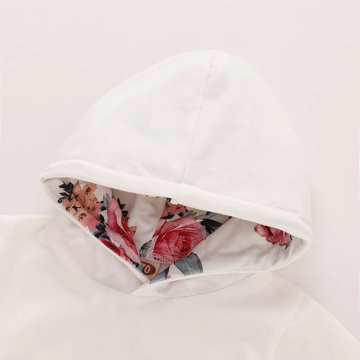 White cotton hooded pantsuit for a baby girl on a hanger, showing long sleeves and full-length trousers.