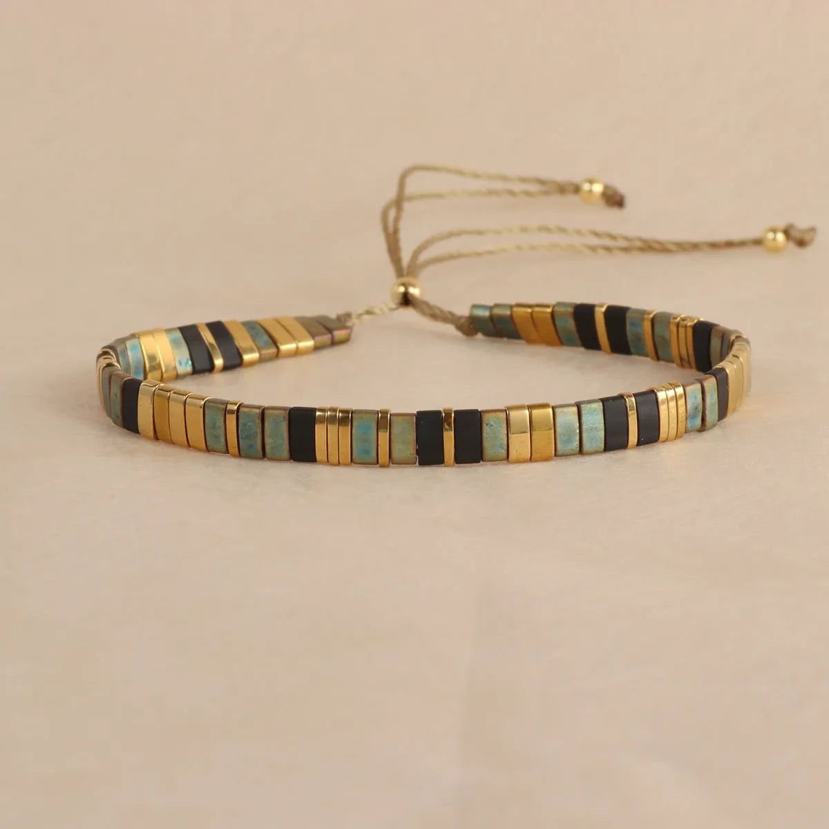 Geometric round glass bead bracelet in five colour options on a wrist.