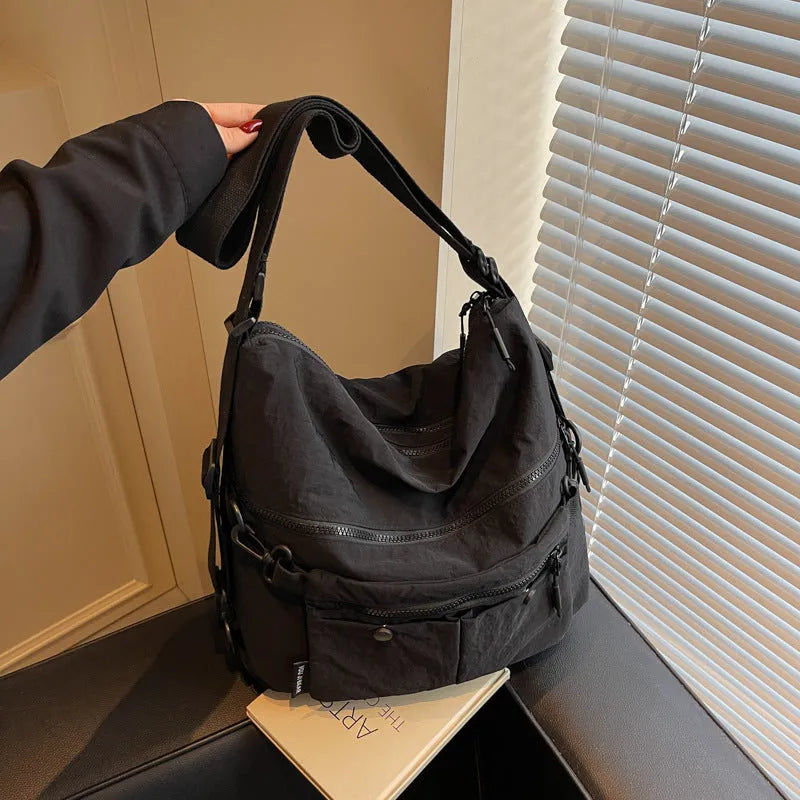 A square-shaped nylon crossbody bag for women in a choice of colours, showing shoulder straps and external pocket.