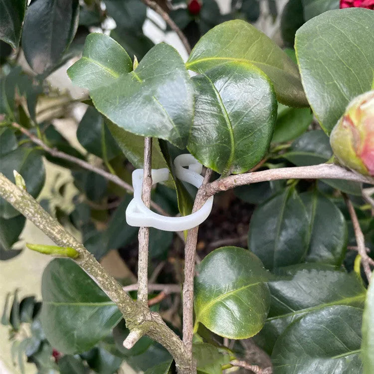 Small green plastic plant clip shaped like a cat, shown next to a plant stem.