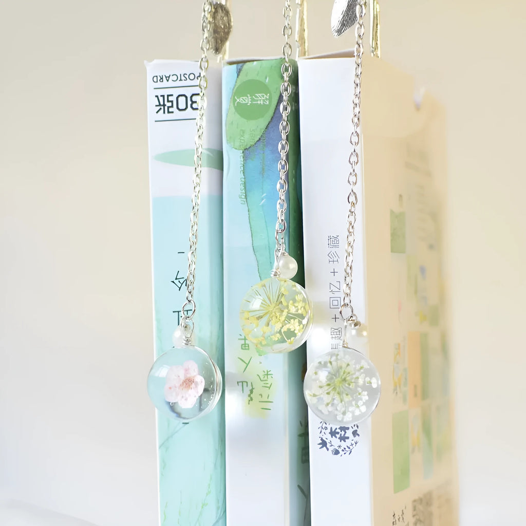 Close-up of a dried flower specimen sealed within a slim, silver-toned alloy metal bookmark.