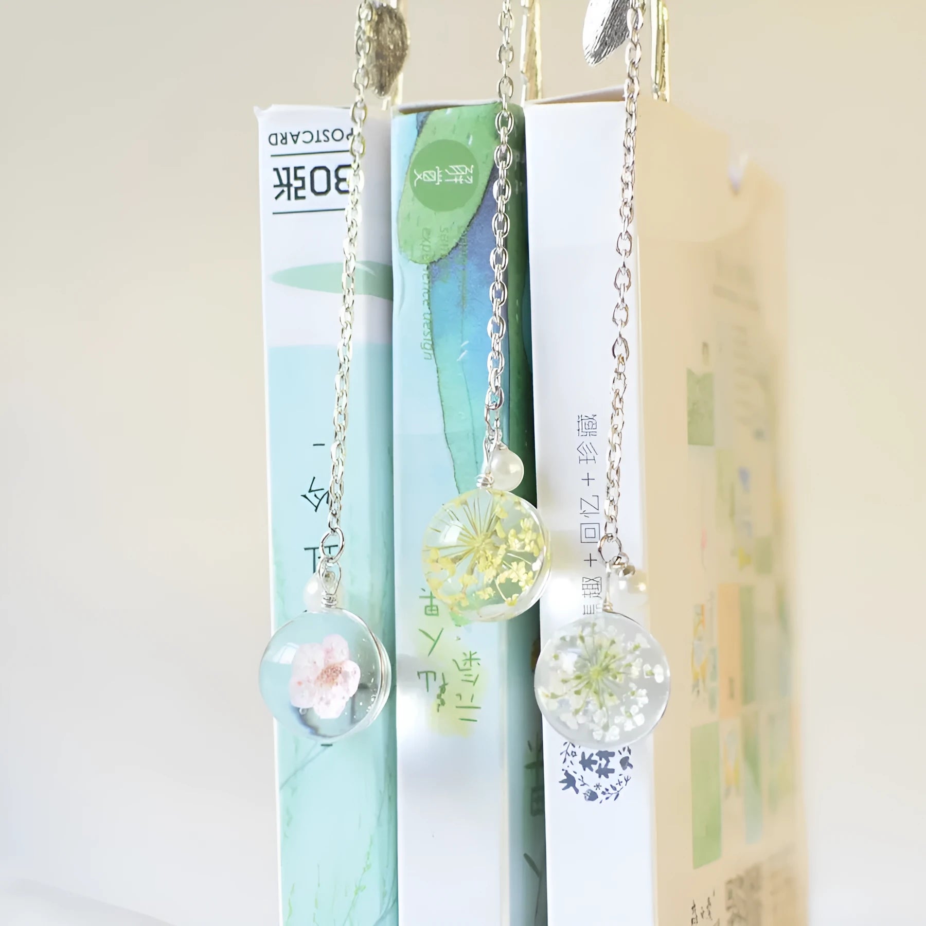 Close-up of a dried flower specimen sealed within a slim, silver-toned alloy metal bookmark.