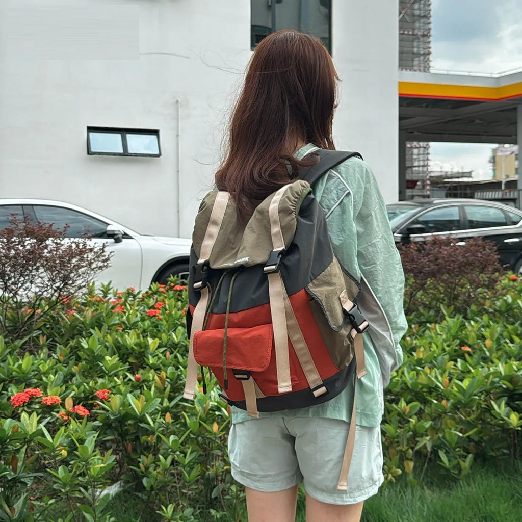Orange and green contrast colour outdoor backpack with multiple compartments, shown from the side.