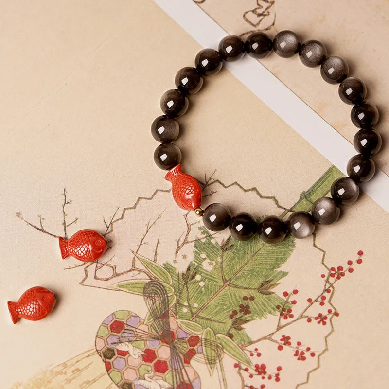 Natural black obsidian round bead bracelet with red cinnabar fungus decorative elements.