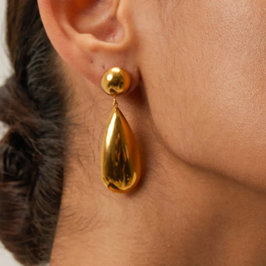 Gold coloured stainless steel earrings with a geometric hemisphere and water drop pendant design.