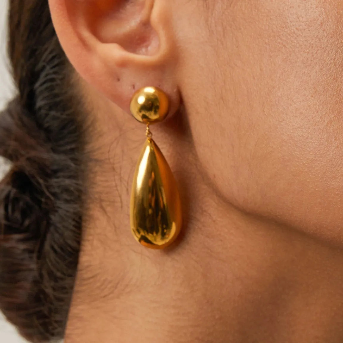Gold coloured stainless steel earrings with a geometric hemisphere and water drop pendant design.
