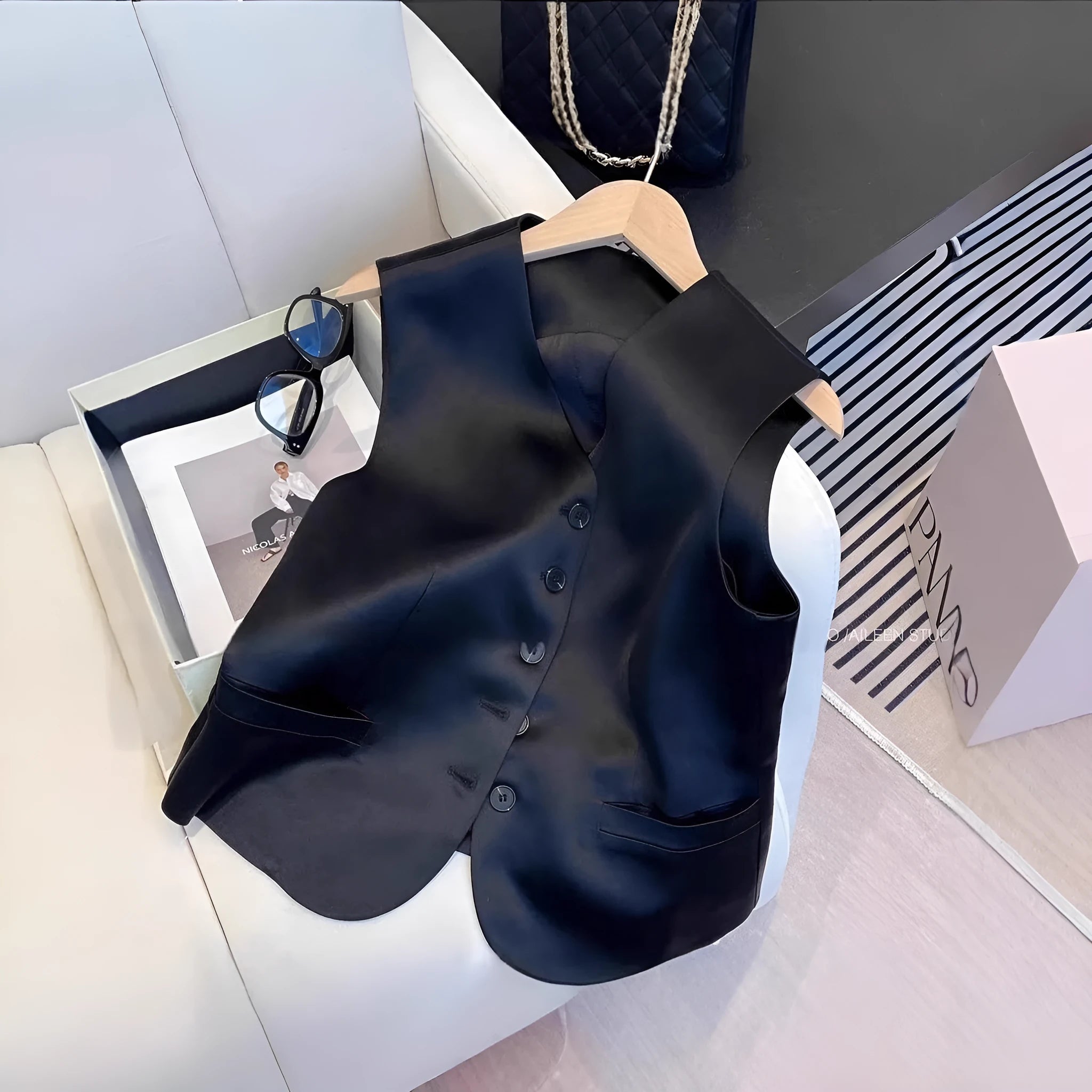 Black satin ladies sleeveless vest with V-neck and loose fit on a hanger.