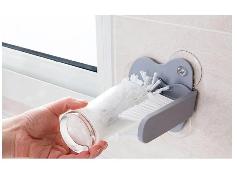 Grey kitchen cleaning brush with two brush heads and suction cups for wall mounting